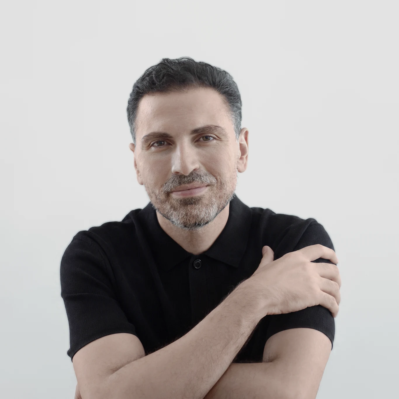 Osama Almughanni, smiling, arms folded, in a black polo shirt.
